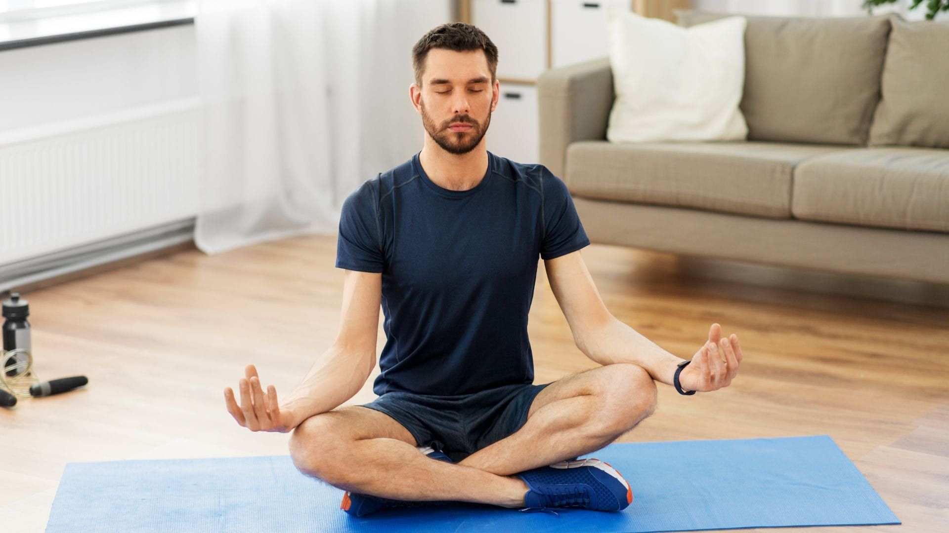 Hombre sentado en el suelo con las piernas cruzadas realizando la guía de meditación para principiantes.
