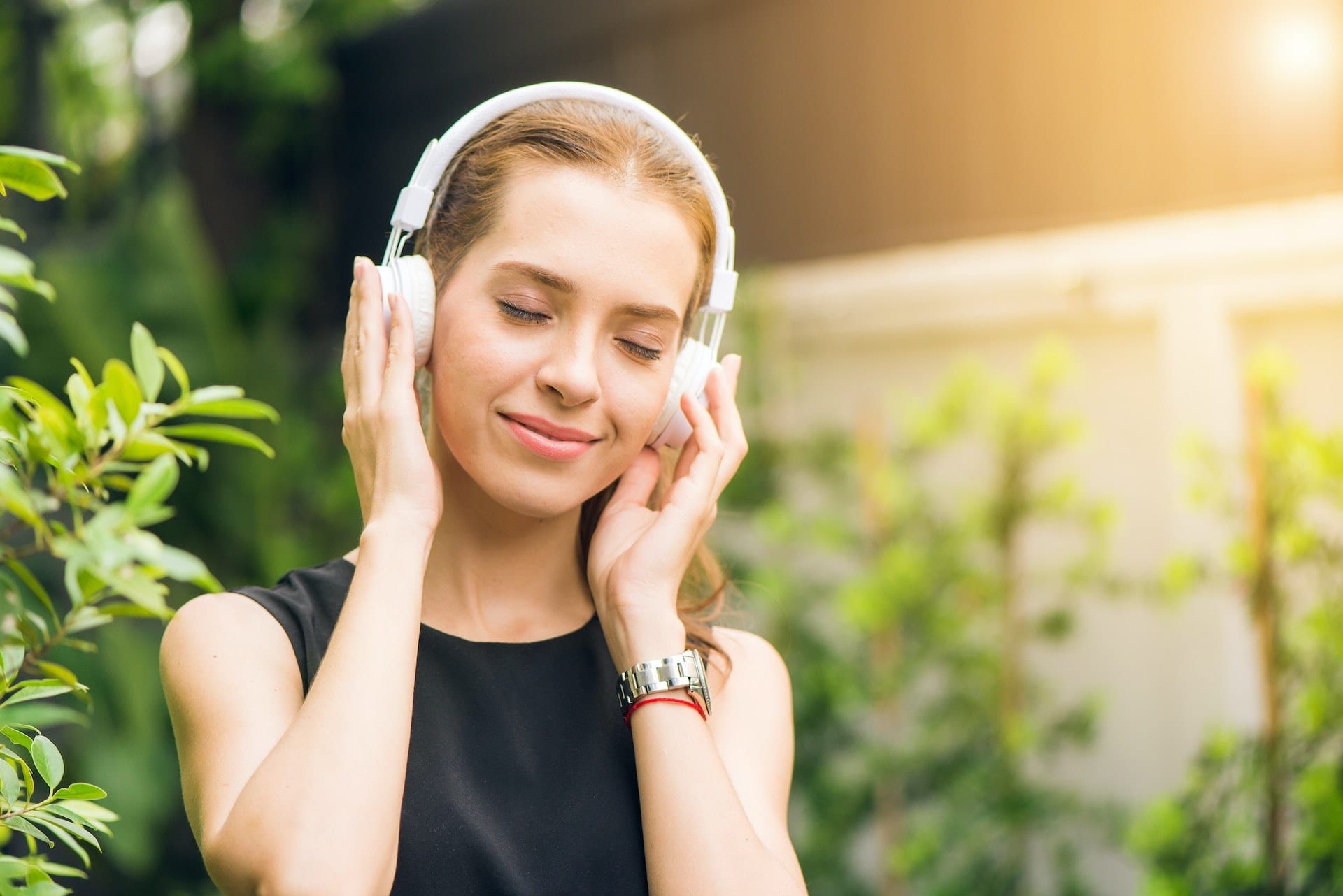 Mujer siguiendo la práctica de meditación para principiantes en la naturaleza con unos cascos.