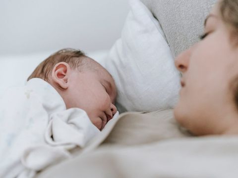 Madre tumbada junto a su bebé dormido